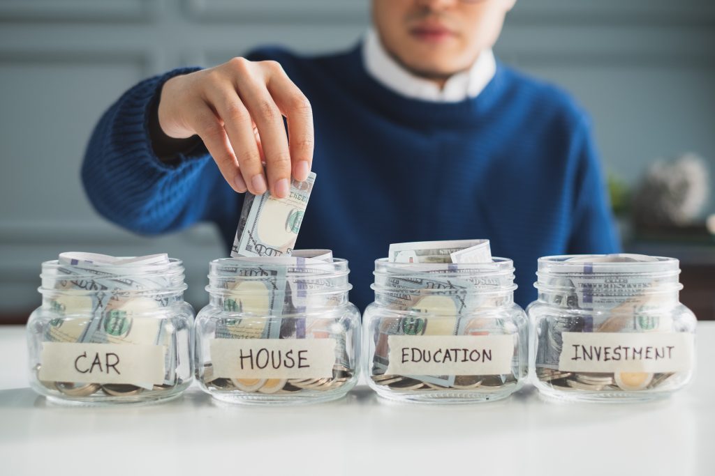 Man putting money into a jar.
