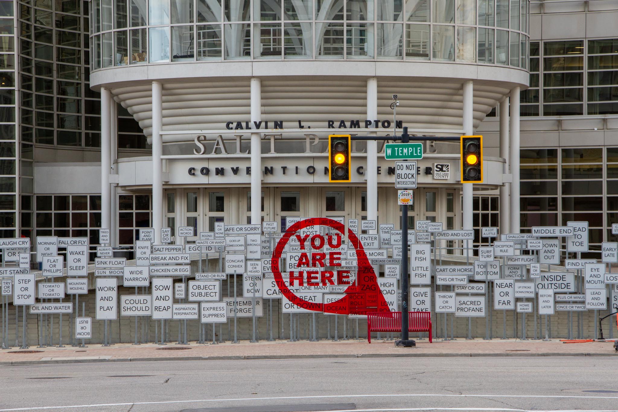 A traffic signal in front of the Salt Palace Convention center and an art exhibit that reads "You Are Here."