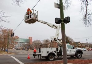 Signal technician using a scissor lift to complete a periodic maintenance inspection on a traffic signal.