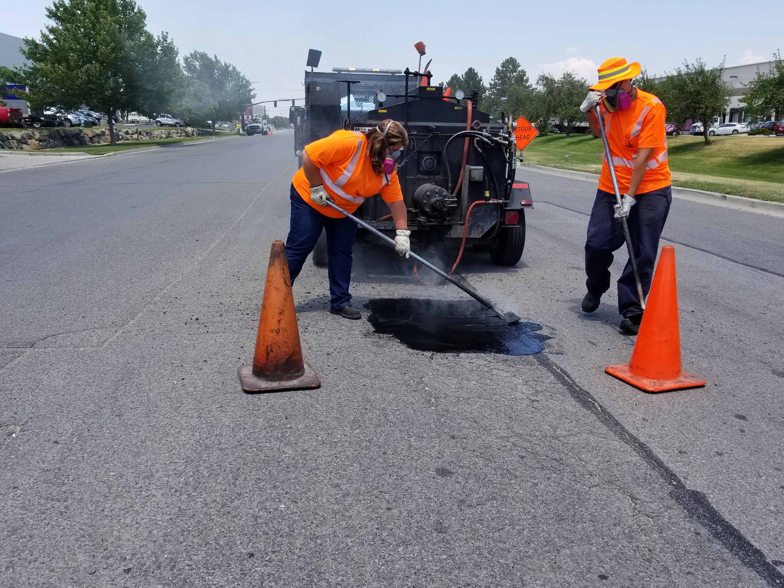 Two members of the Salt Lake City Streets Division repairing a pothole