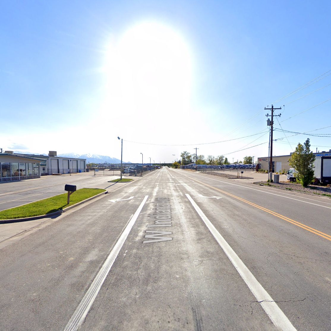 View looking east down West Indiana Avenue near Bending River Road in Salt Lake City, showing a wide street with no sidewalks on the north side. This location is part of a planned project to add sidewalks and extend the 9-Line Trail, improving safety and multimodal connections for students and residents.