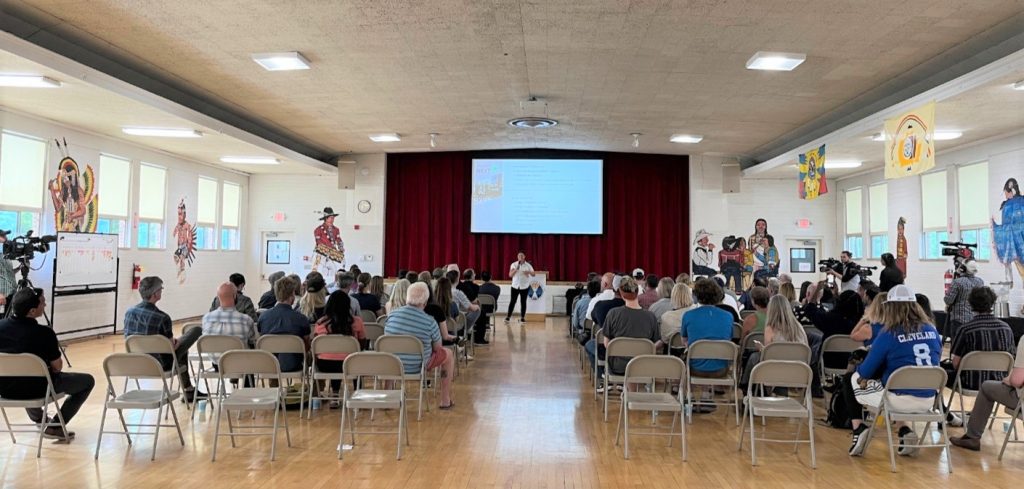 people sitting in metal chairs facing a a presentation