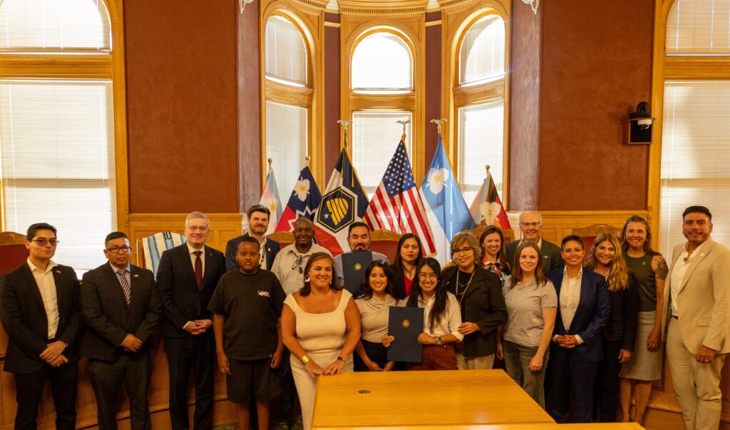 The mayor, along with Council Members, gather with members of Utah Immigrant Advocacy Committee and consul members of the Utah Consular Corp in front of city flags to recognize June as Immigrant Heritage Month.
