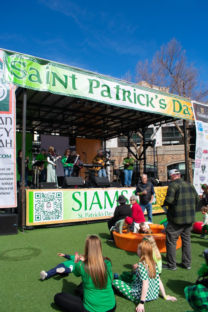 A crowd watching a band play on the Saint Patrick's Day parade stage.