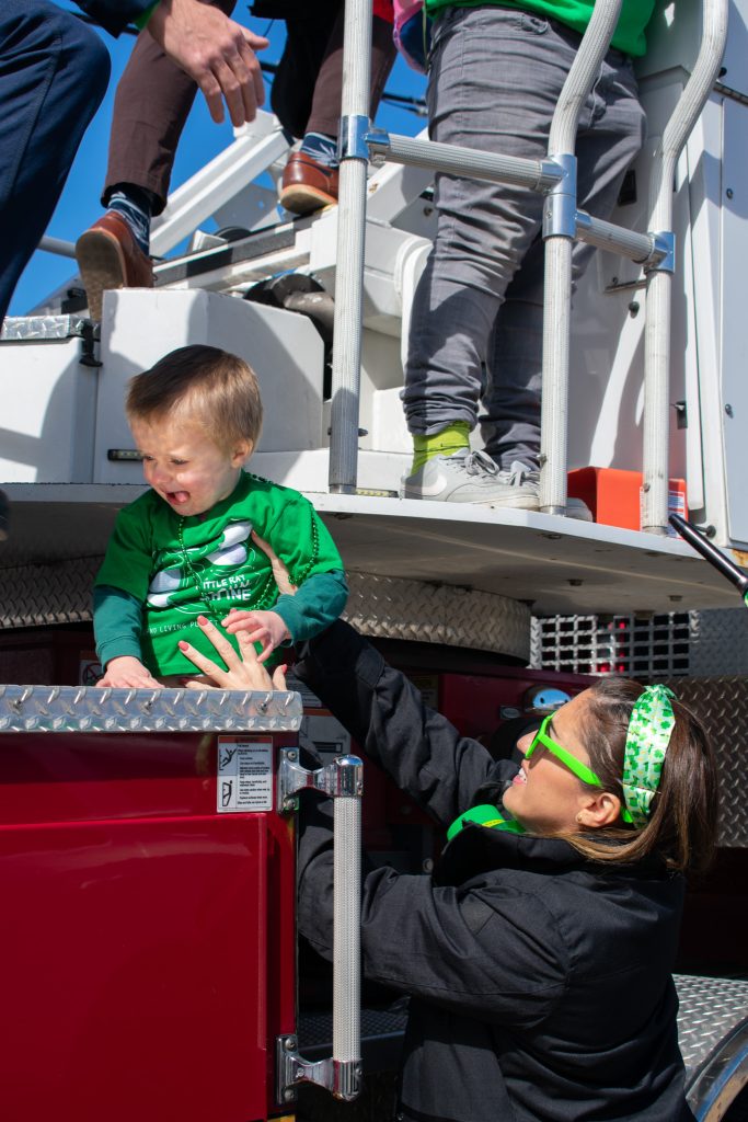 A small child being put on a fire truck for a ride.