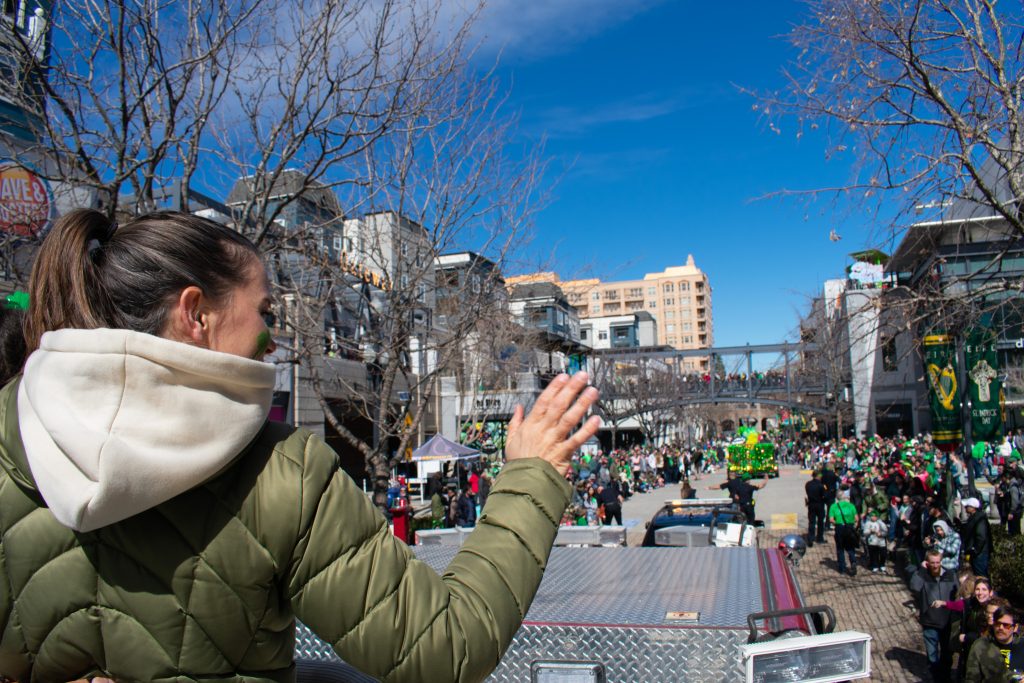 A person waving at the crowd watching the parade.