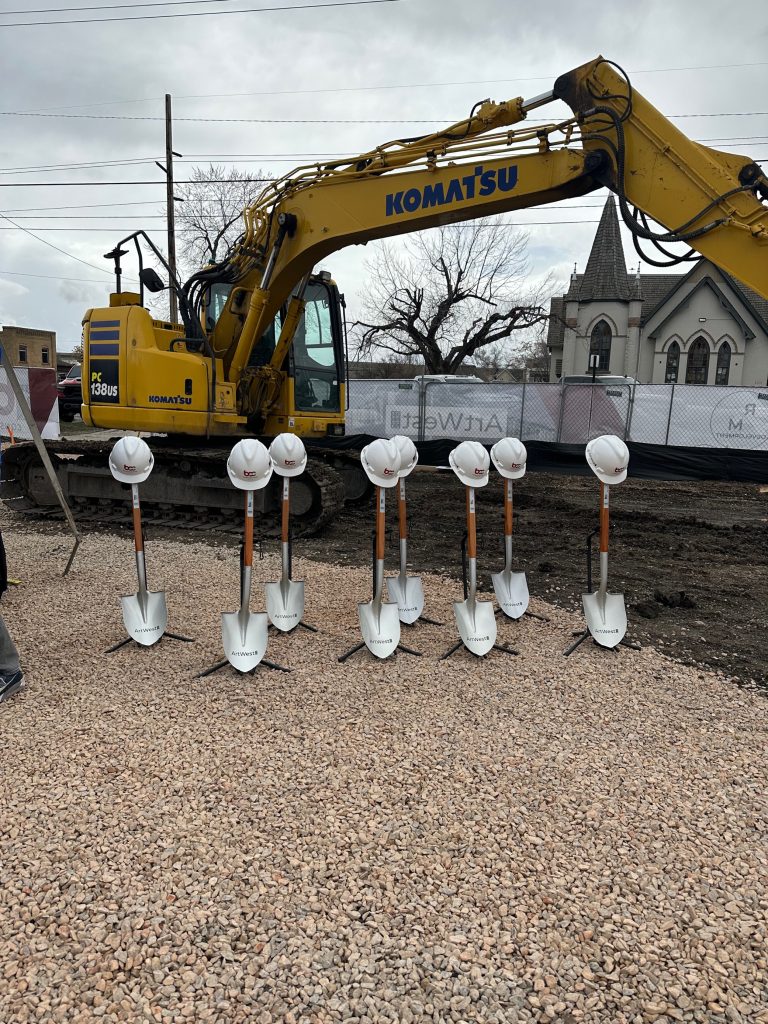 8 shovels being held up on their tips with a stand and hard hats over the handles.