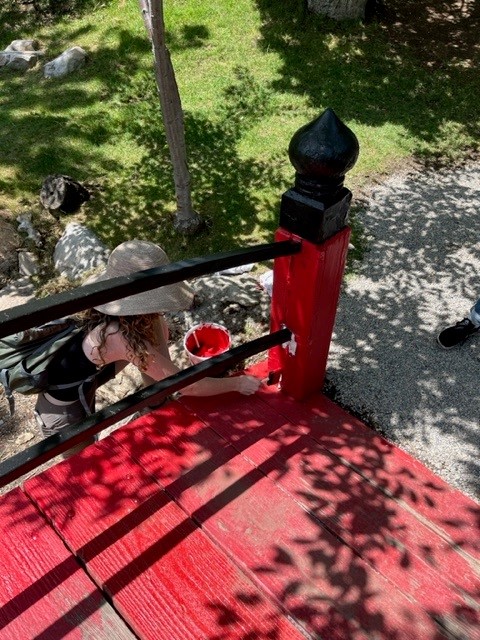 A woman repainting the red bridge.