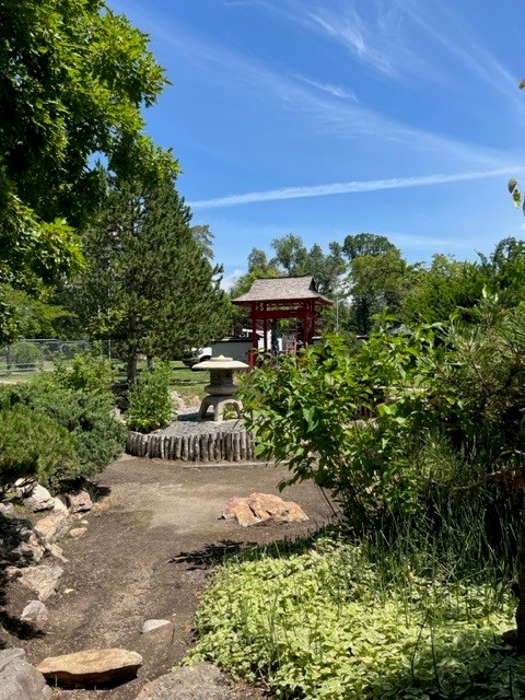 A dry man-made river bed with a view of a Japanese sculpture and a red pavilion.