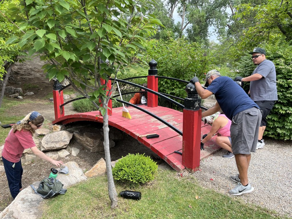 People cleaning a red bridge.