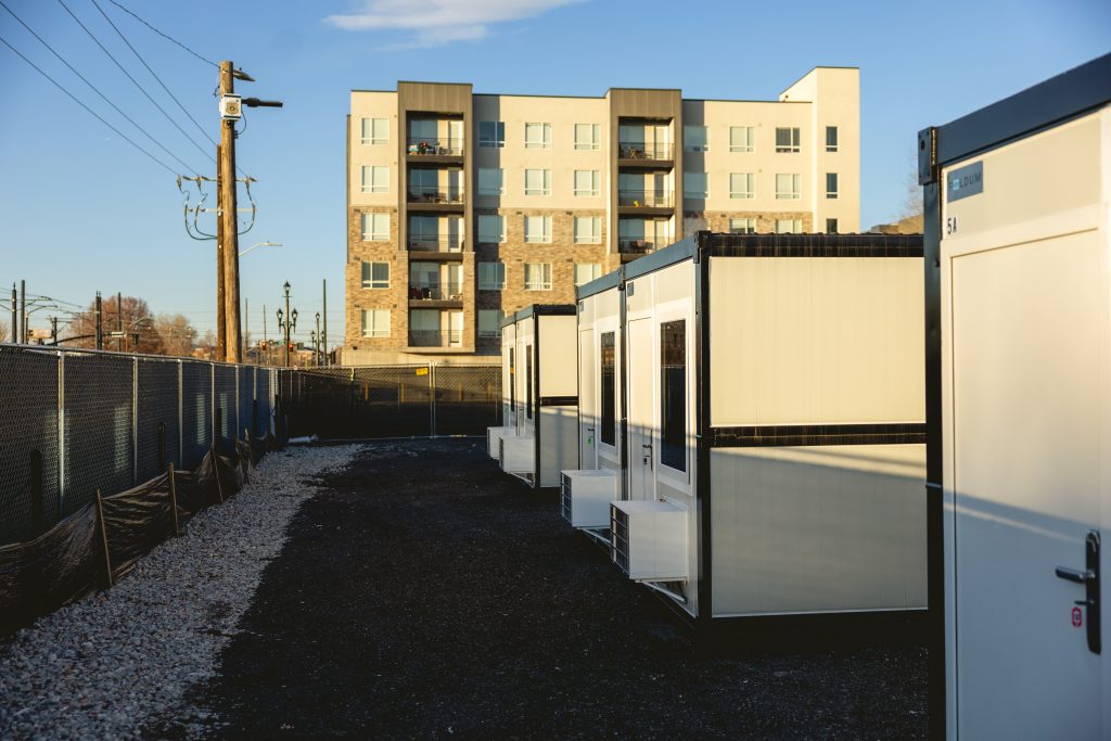 Outside view of temporary micro shelter community with building in the background