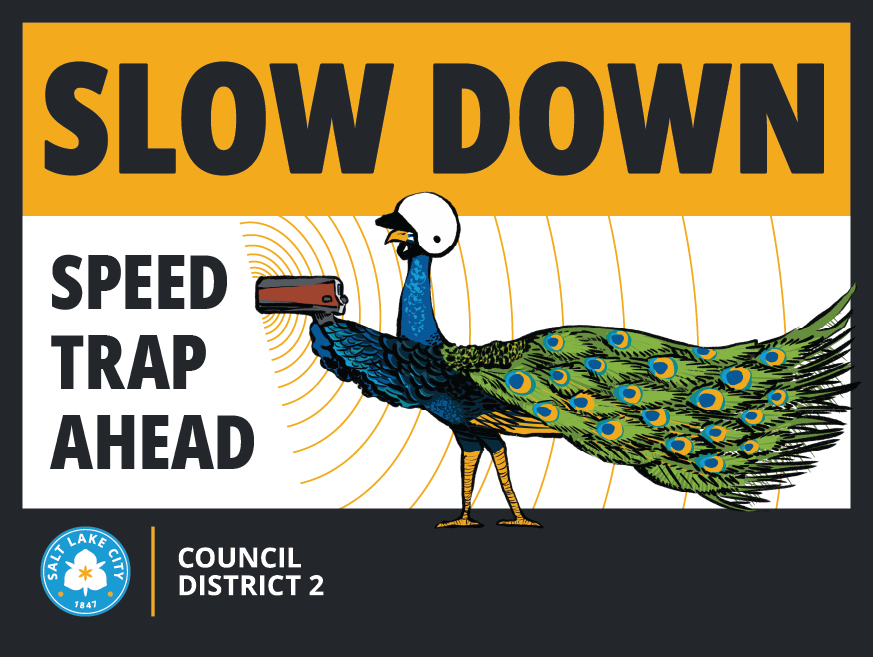 Sign with “SLOW DOWN: SPEED TRAP AHEAD” and an illustrated peacock holding a radar speed gun. Salt Lake City Council District 2.