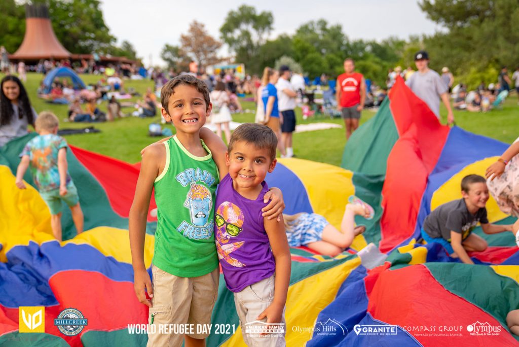 Two children smiling with other children and families in the background