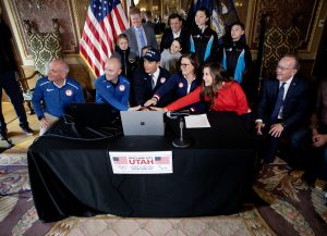 Salt Lake City Mayor Erin Mendenhall (in red) helps press the button to submit the bid to bring the Olympic Games back to Utah.