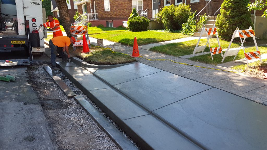 Concrete crews shaping an drive approach, curb, and gutter.