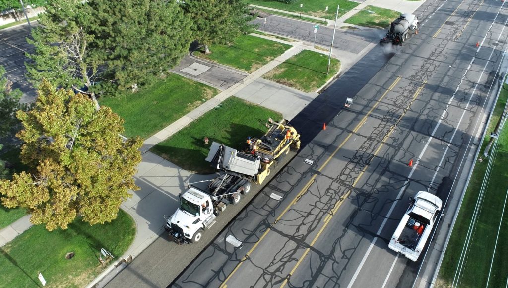 An aerial view of the chipper and oil distributor trucks laying down a fresh coat of chip seal.