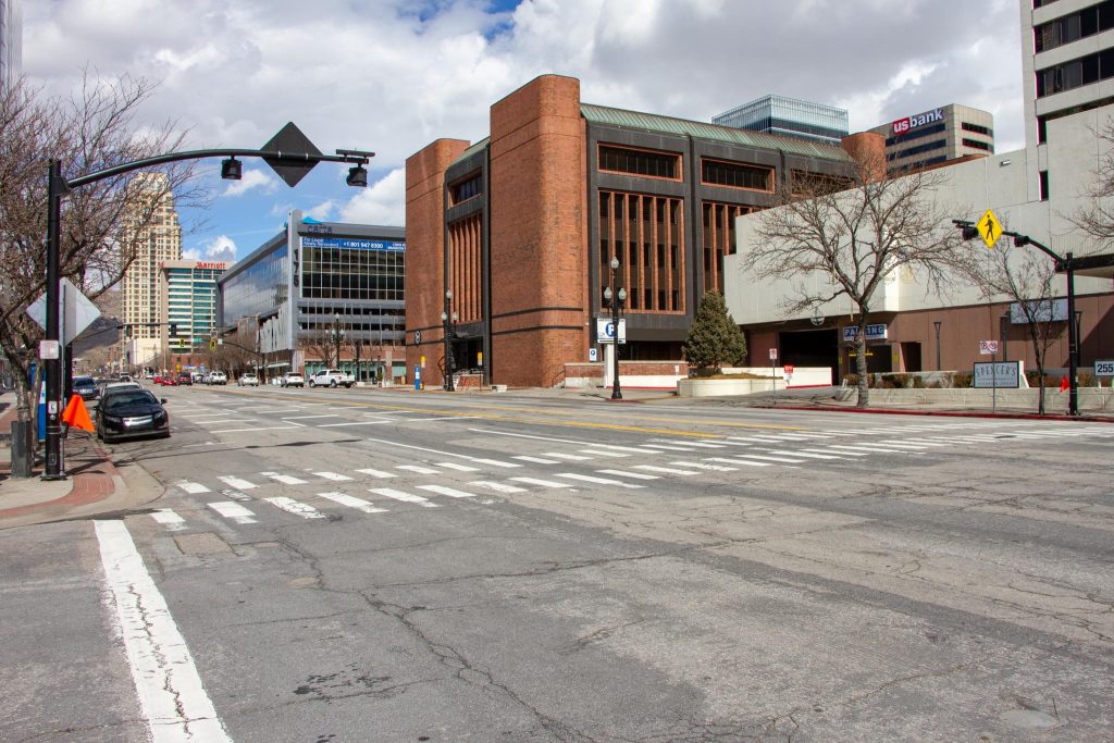 A crosswalk across West Temple with an old style of signalized pedestrian flashing lights on each side of the road.