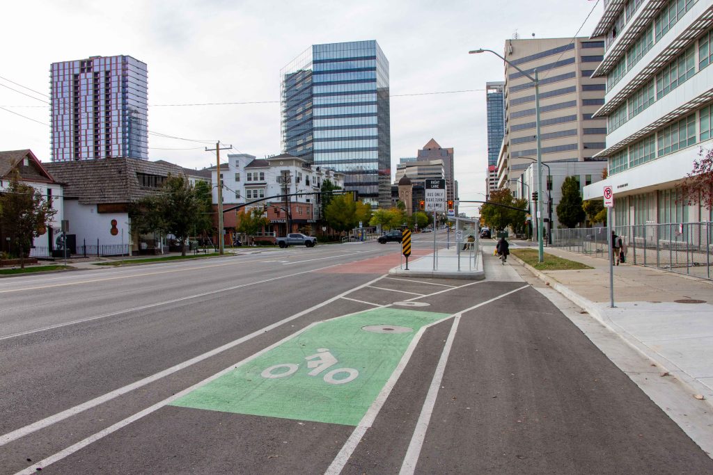A picture of a bike lane on 200 South that dips behind a bus boarding island at an intersection.