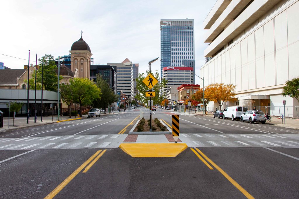 A picture of a crosswalk on 200 South, complete with flashing crosswalk signs and a landscaped pedestrian refuge island.