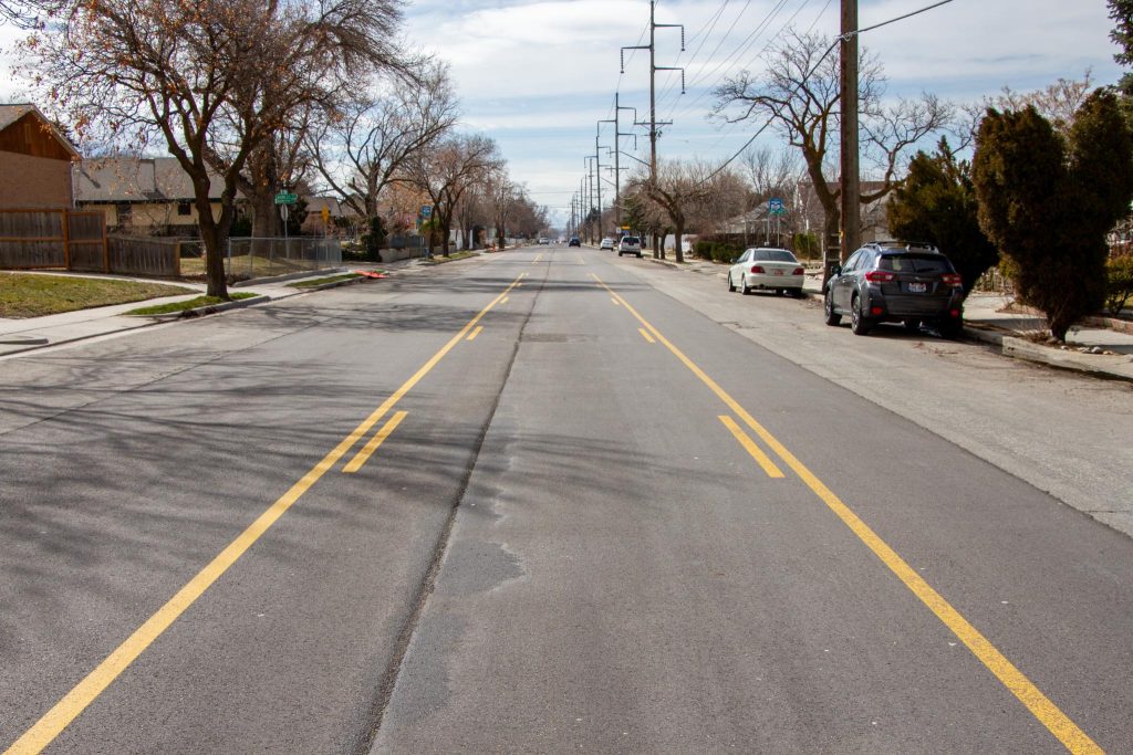 900 East existing conditions looking south. There are two vehicle travel lanes, one in each direction, separated by a two way left turn lane.