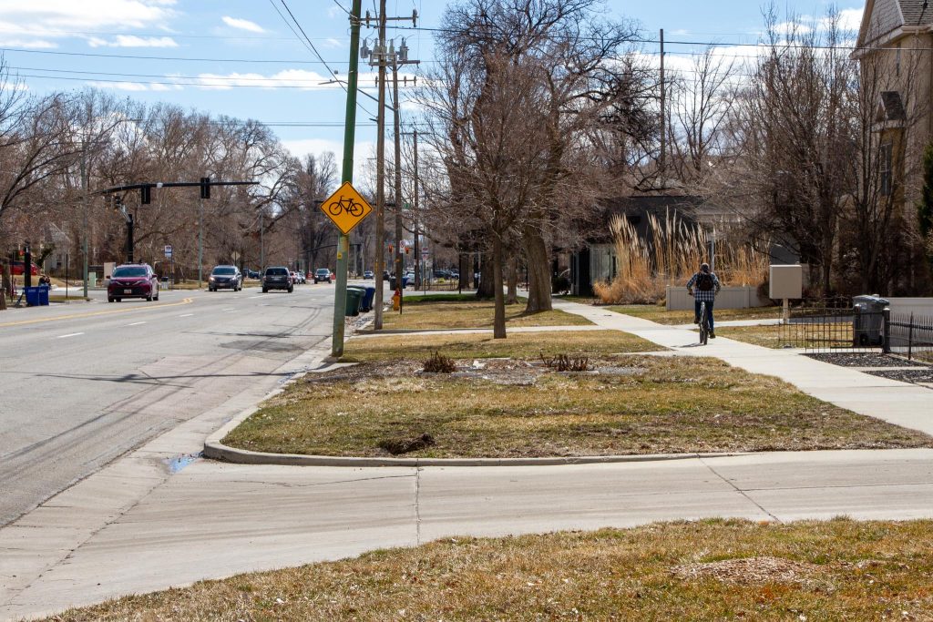 A cyclist avoiding riding on 500 East by riding on the sidewalk adjacent to the roadway