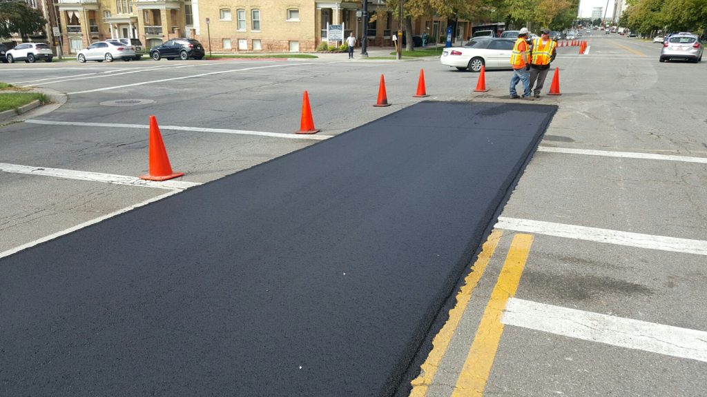 A fresh section of asphalt surrounded by existing pavement on 100 South. This is part of an inlay project.