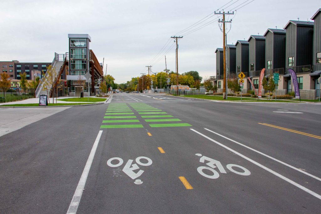 A picture of new asphalt and bike lanes on 300 North with the 300 North pedestrian bridge in the background.