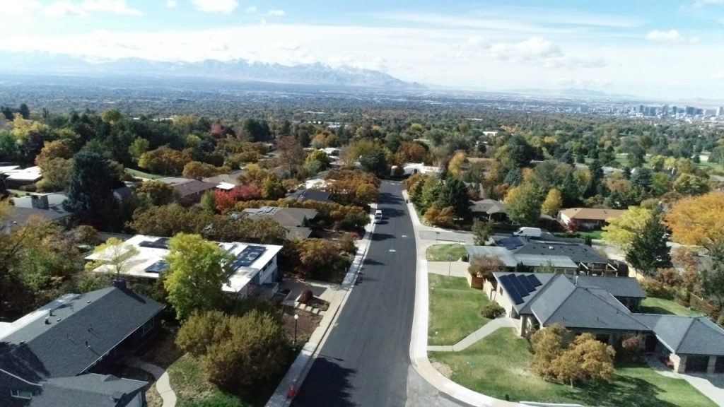 Aerial view of Oquirrh Drive after reconstruction, featuring freshly paved asphalt, updated curbs, and surrounding fall-colored trees in a quiet residential neighborhood.