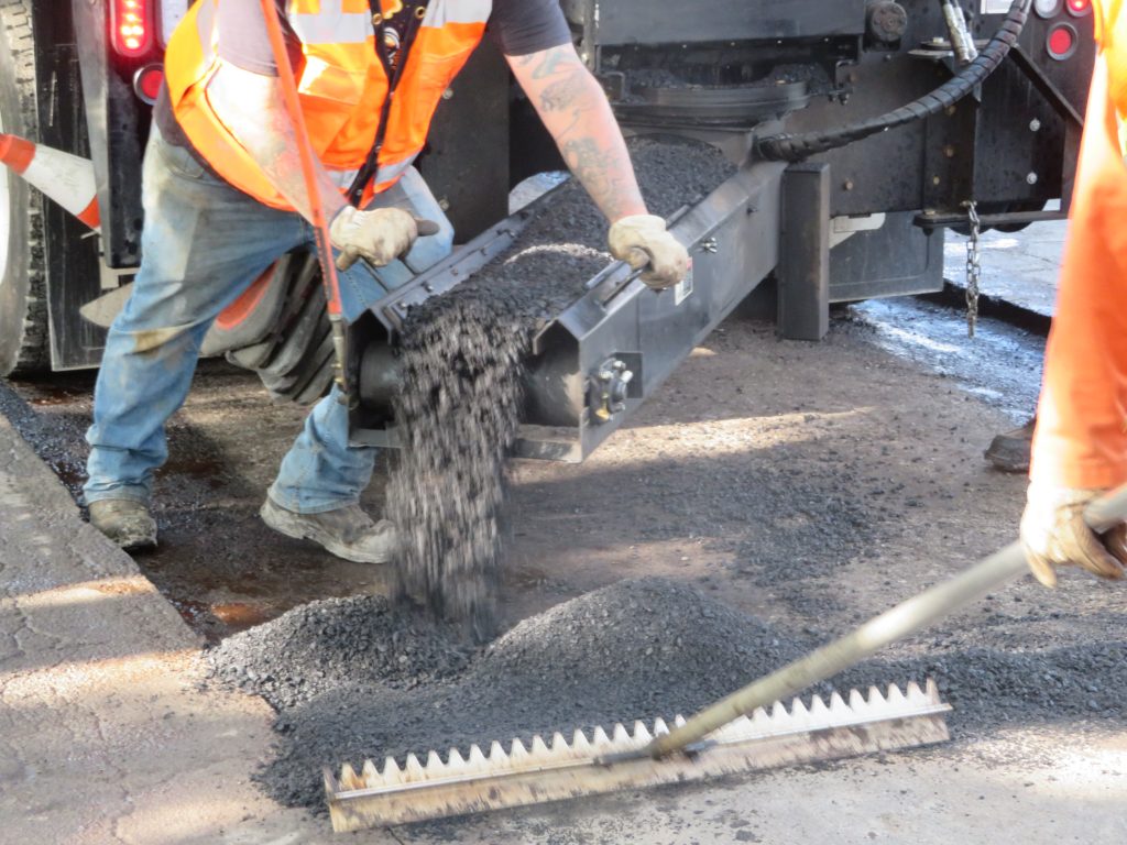 The patch truck adding new asphalt after the area was prepped with oil