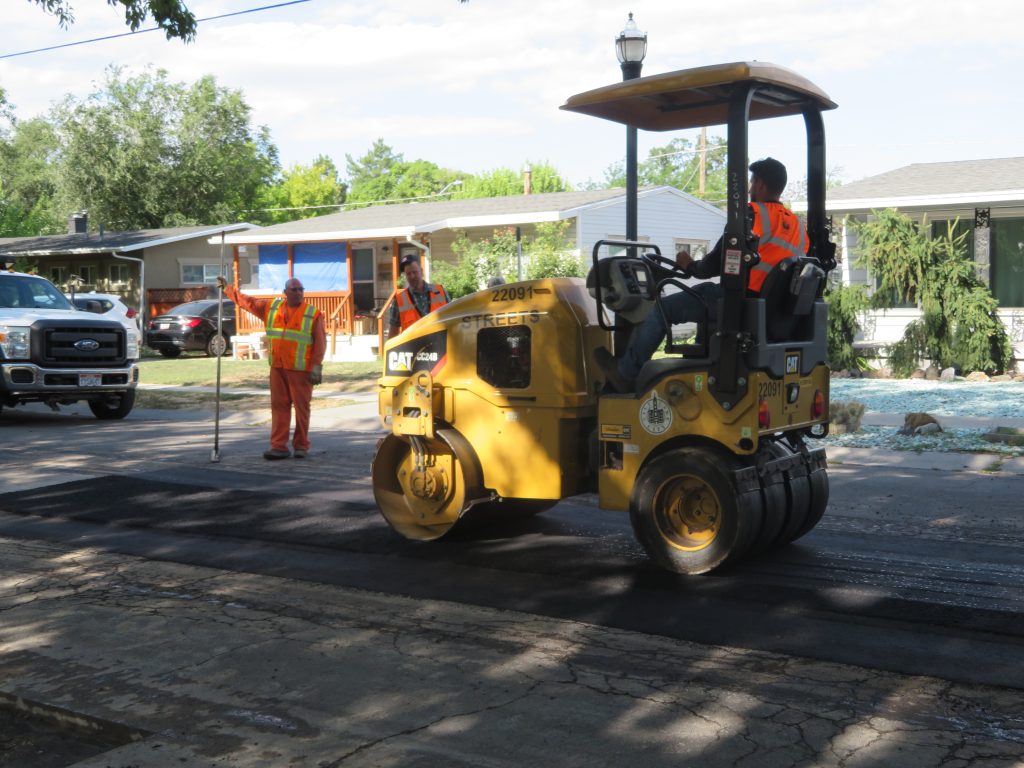 The roller smoothing out the asphalt, resulting in the completed repair