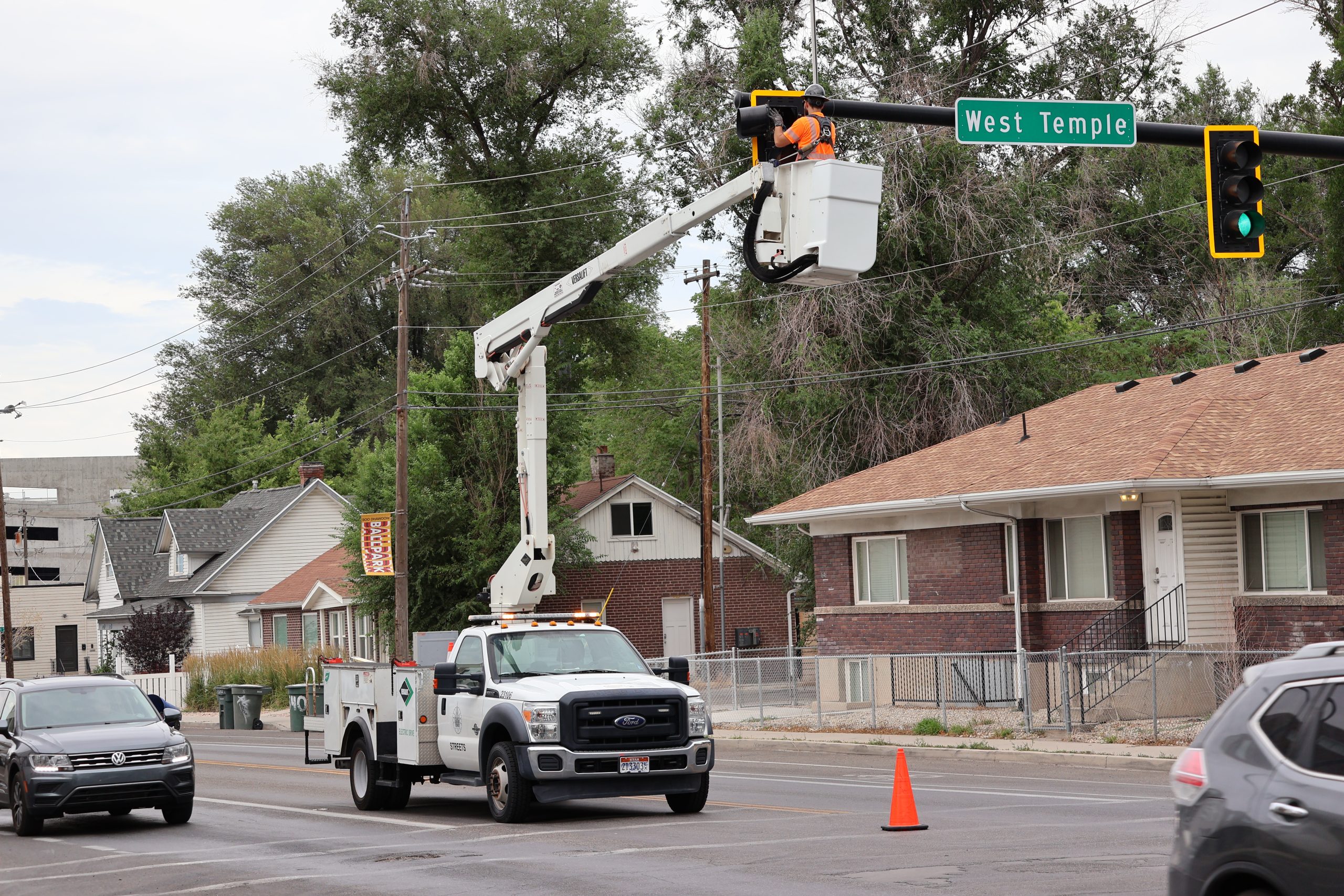 Streets' Signal Team using a crane arm on a maintenance truck to perform maintenance on a traffic signal high in the air.