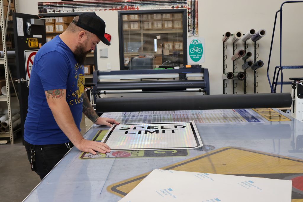 A Streets employee making a speed limit sign.