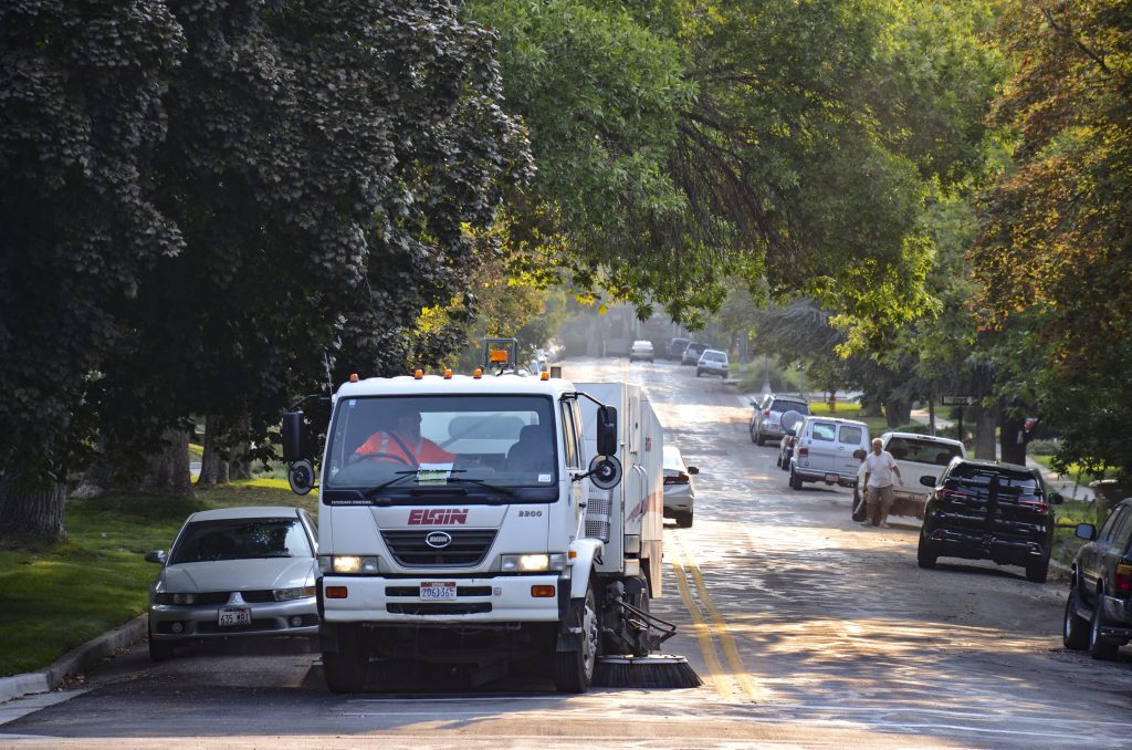 Street sweeper machine driving down neighborhood road in Salt Lake CIty sweeping the street.
