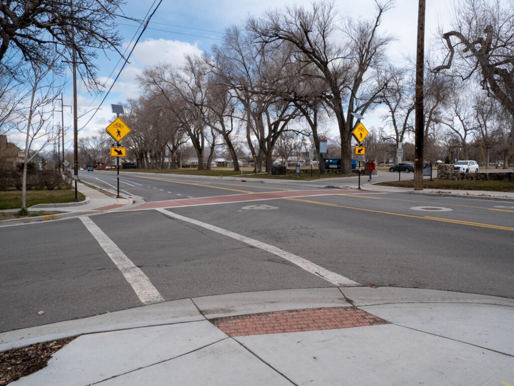 A crosswalk on 900 East near Fairmont park. The crosswalk has flashing signs (RRFBs) that are activated by a push button.