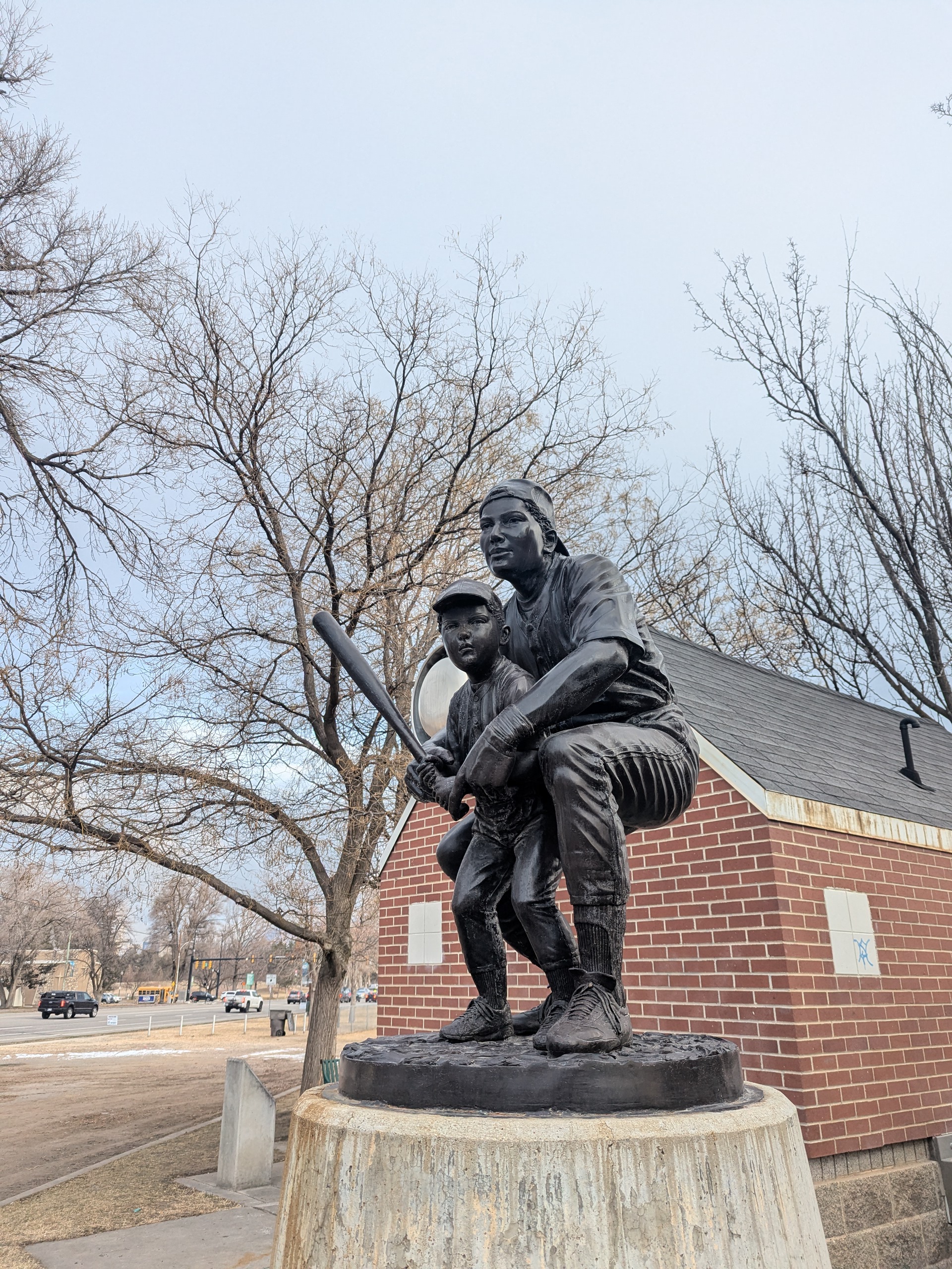 Photo shows a metal statue of Herman Franks kneeling to help a child with a baseball bat
