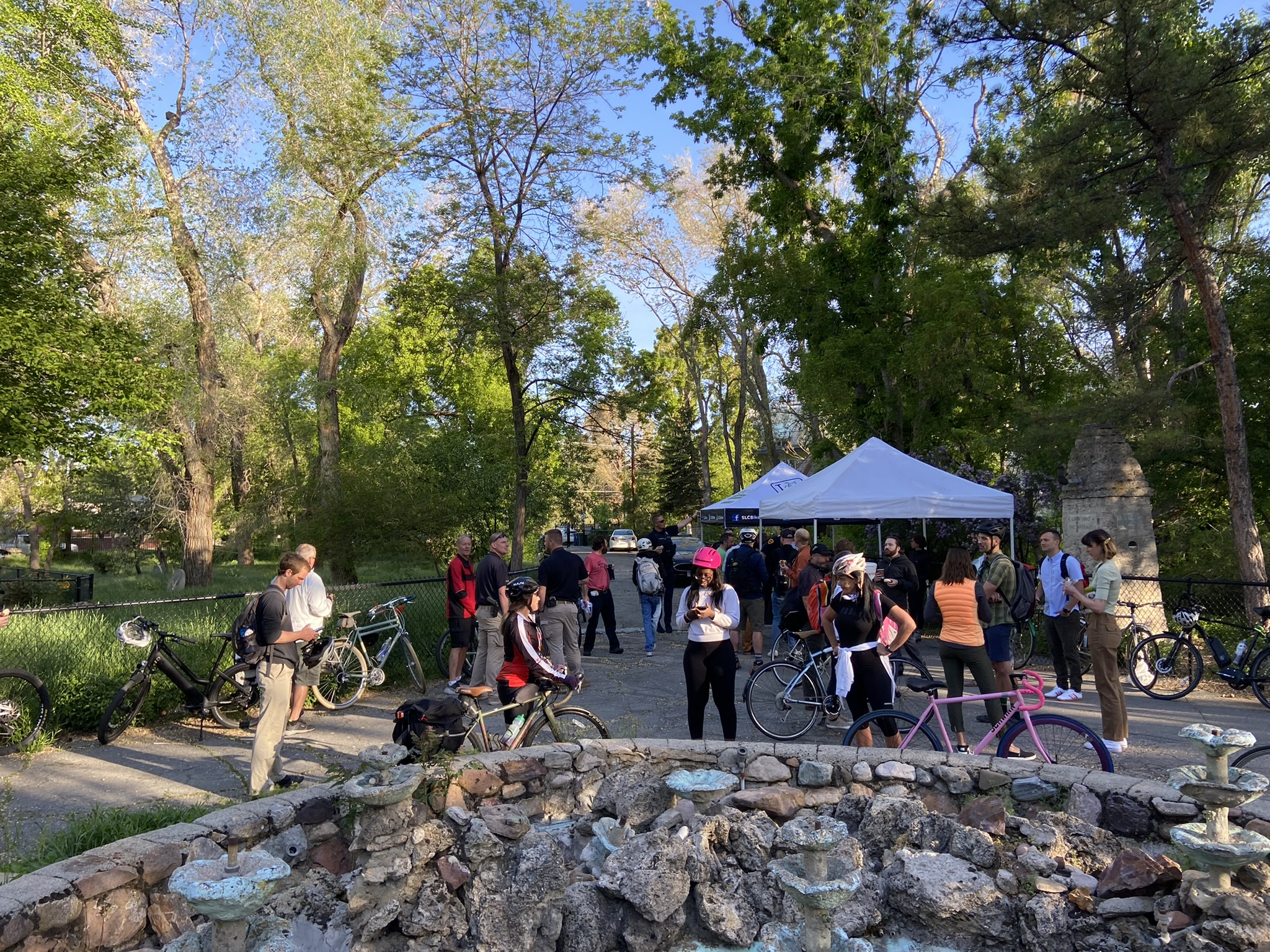 Crowd gathered for a biking event. Canopy tents are set up, and many people are wearing helmets and carrying bicycles.
