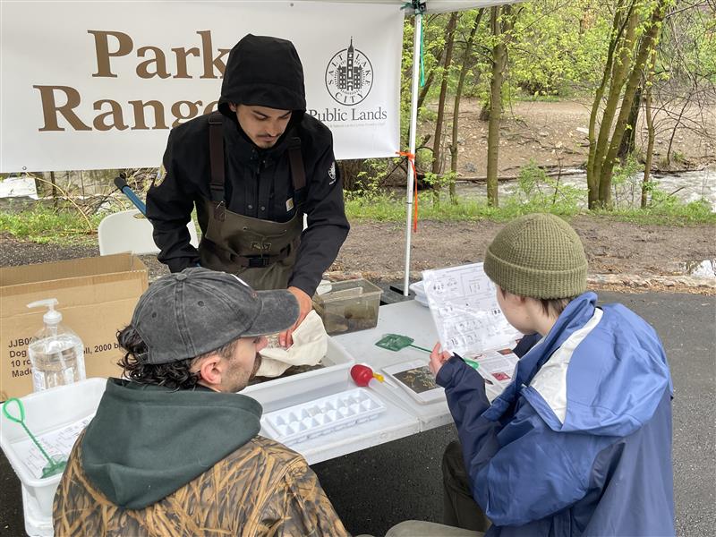 a park ranger stands behind a table with constituents on the other side participating in an activity. 