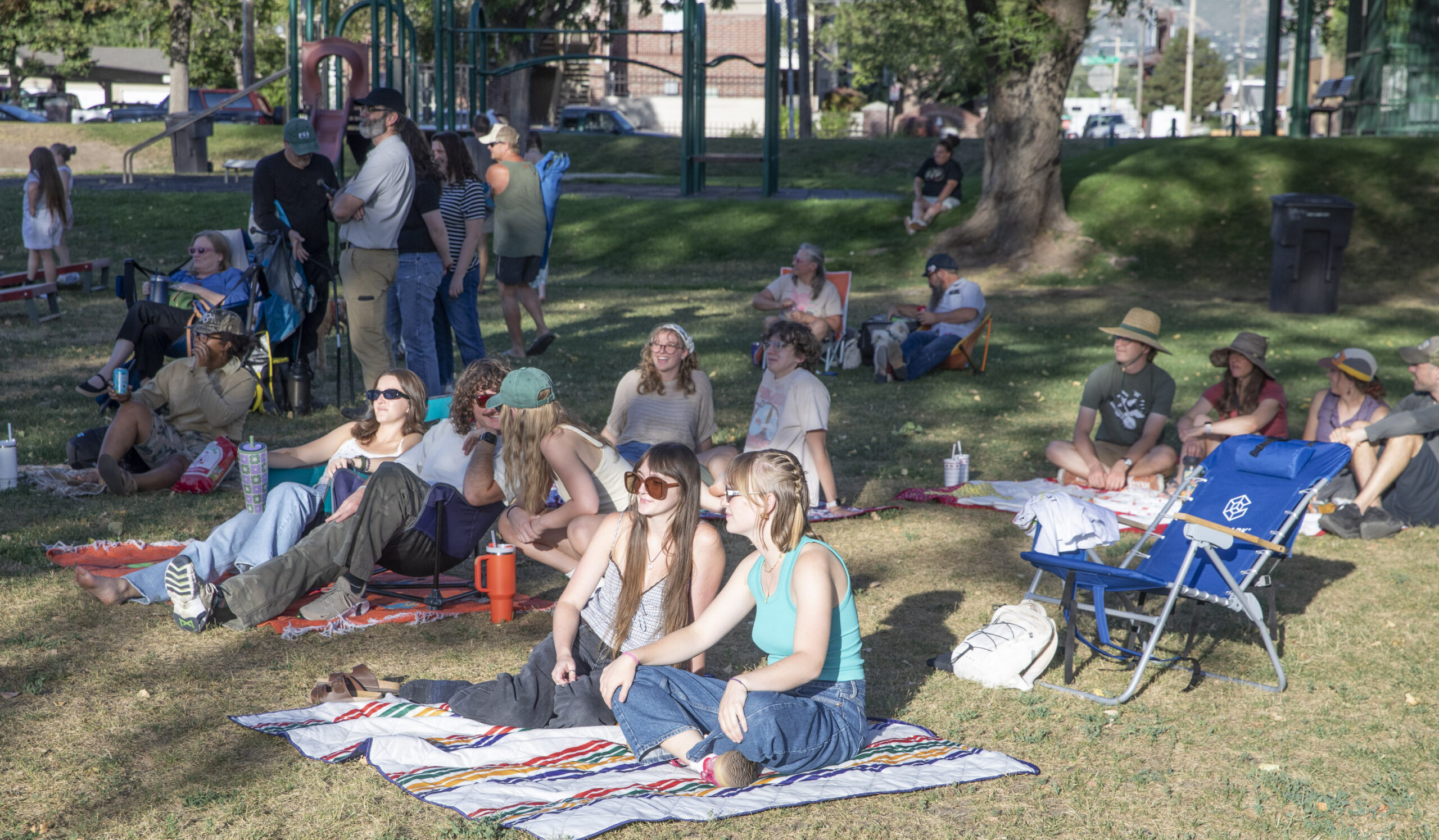a group of people in blankets in a park all talking and enjoying a concert