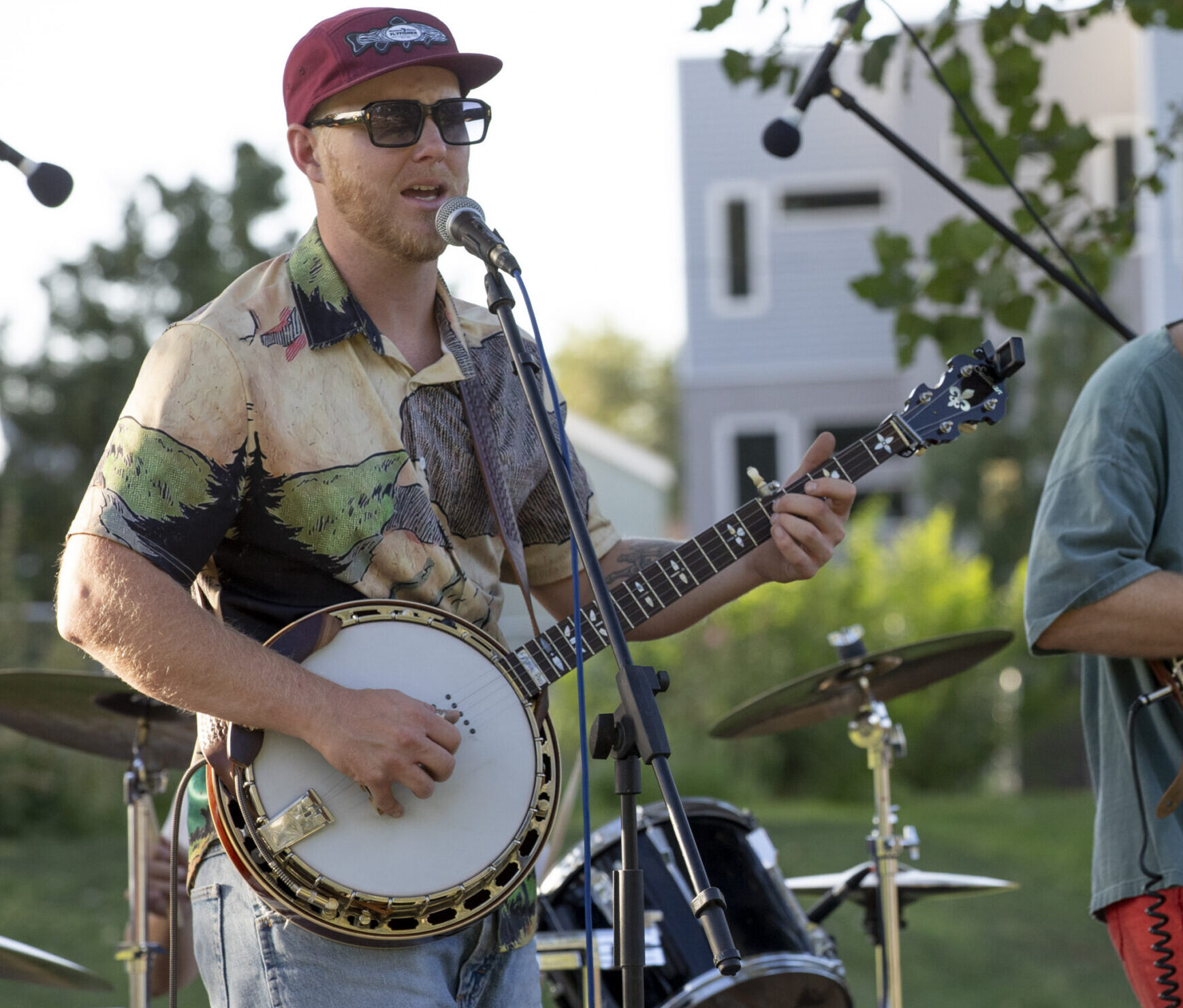 a man sings into a microphone while playing the banjo