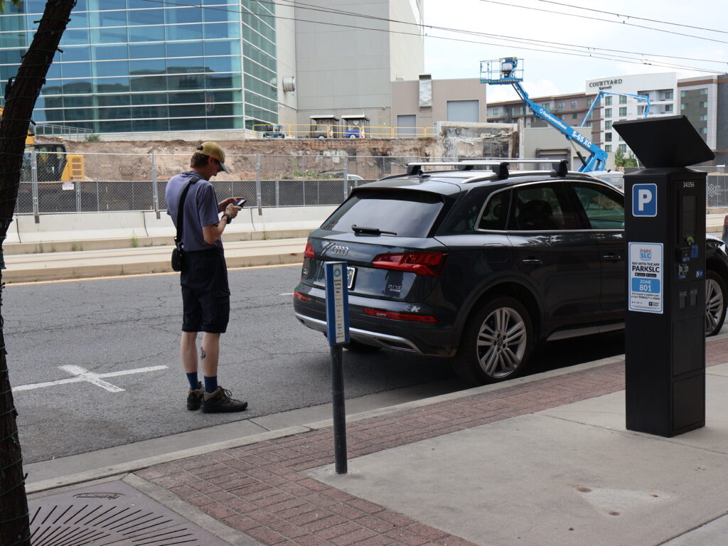 Enforcement officer inputting information into their mobile device as they write a parking ticket.