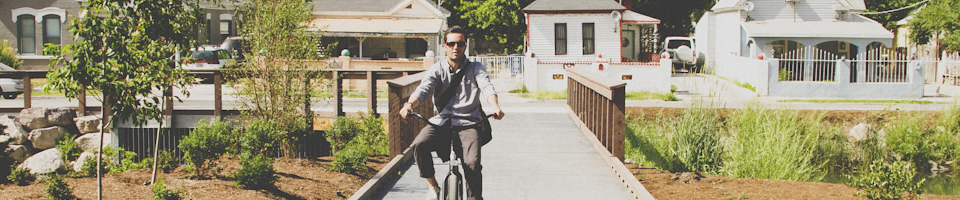 A picture of a person riding a bicycle along an urban trail.
