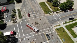 An aerial image of several large vehicles like fire trucks and busses navigating a pop-up roundabout demonstration at the intersection of 900 South and 1100 East.