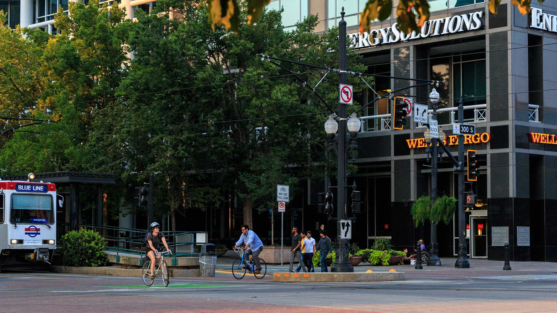A picture of an urban setting with pedestrians, cyclists, and the TRAX blue line.