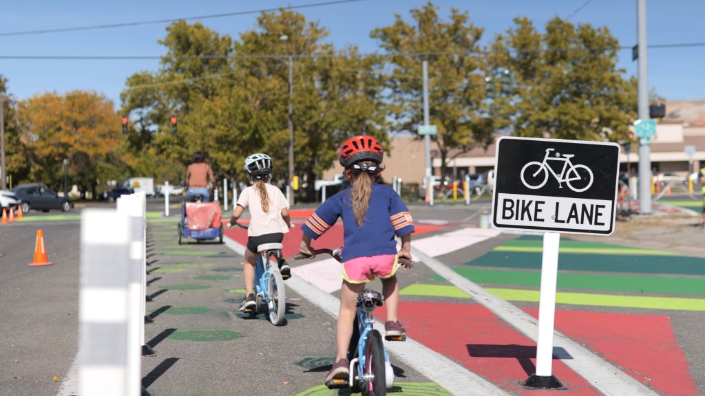 Two kids riding in a popup protected bike lane.