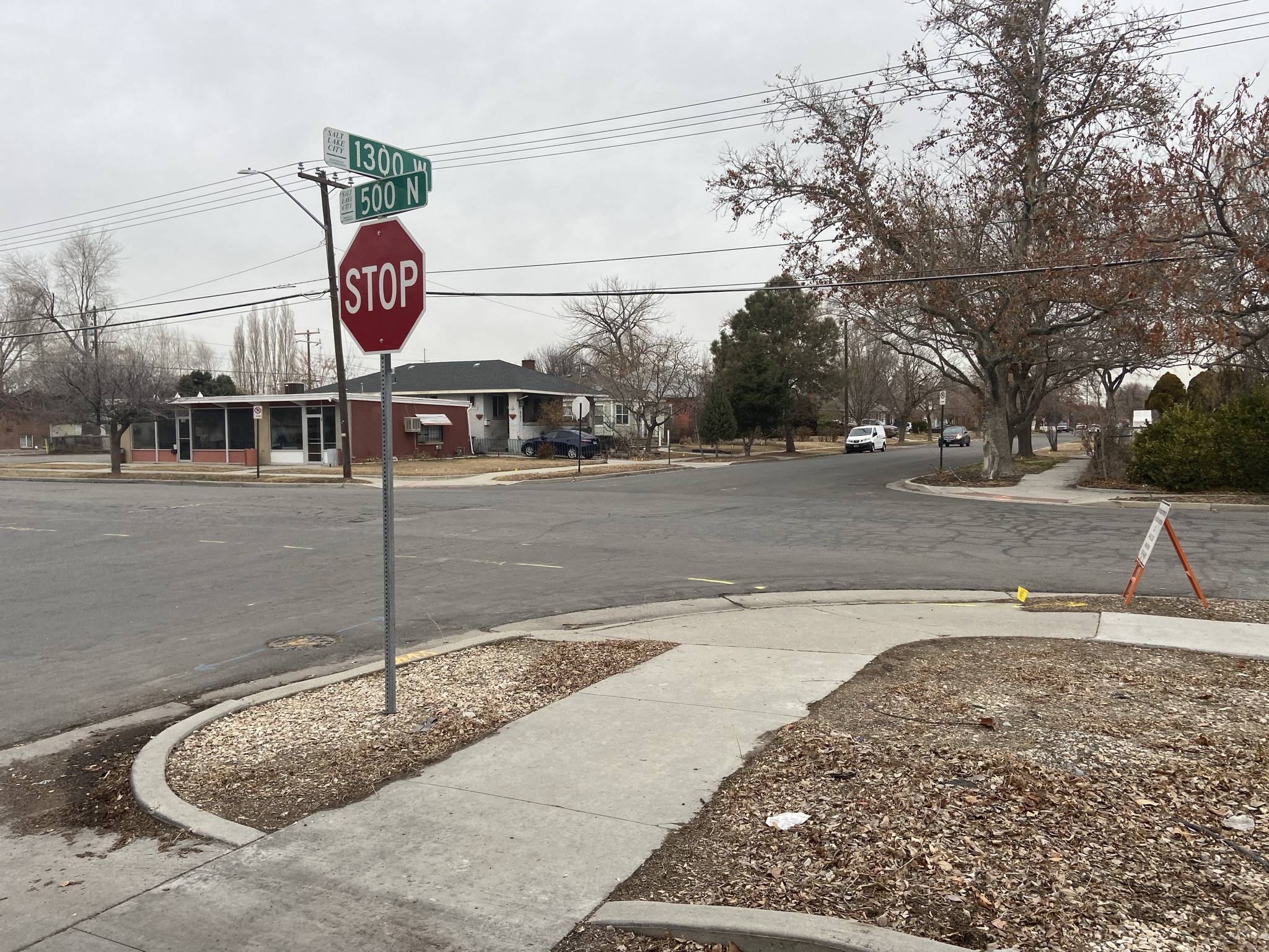 A stop sign at a residential intersection with street signs "1300 W" and "500 N" visible.