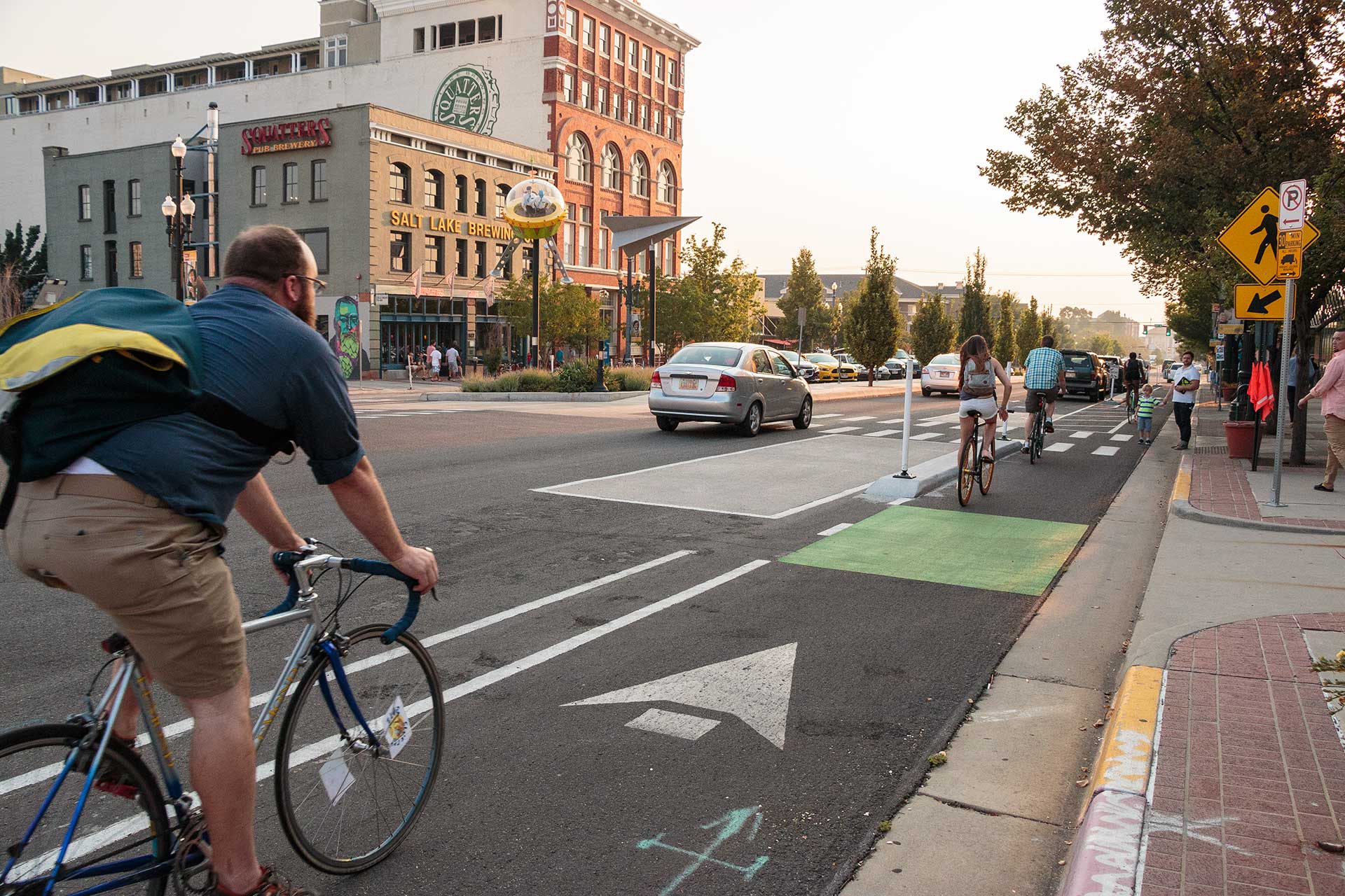 A person riding a bicycle along the protected bike lane on 300 South near Squatters Brewery.