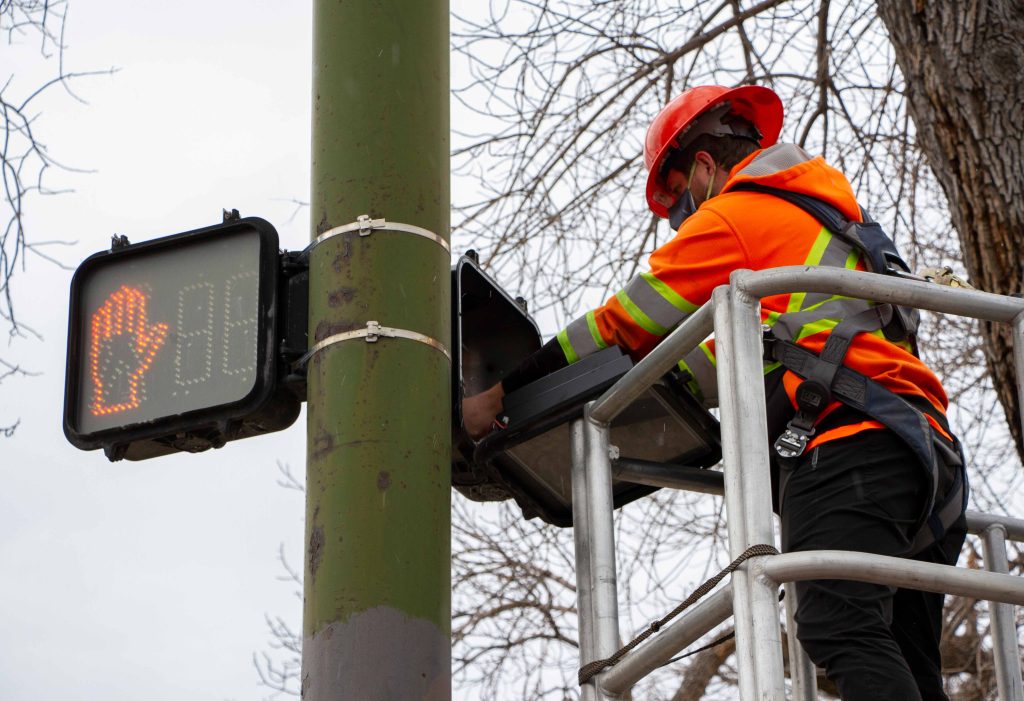 A traffic signal technician completing a periodic maintenance inspection on a pedestrian signal.