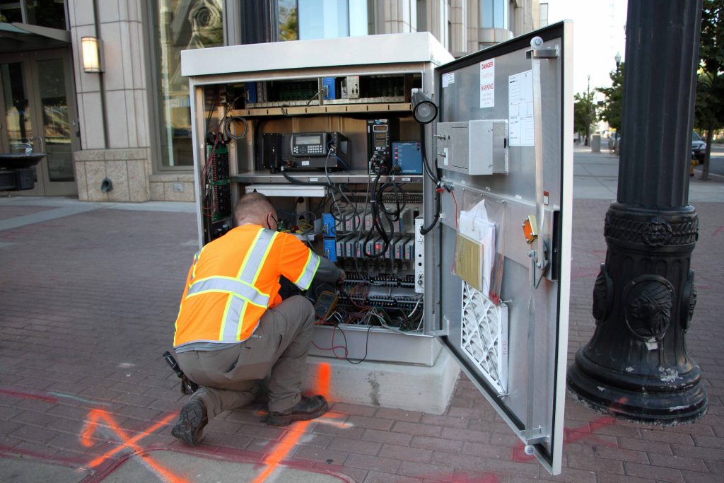 Traffic signal technician completing a periodic maintenance inspection on a traffic signal control box. 