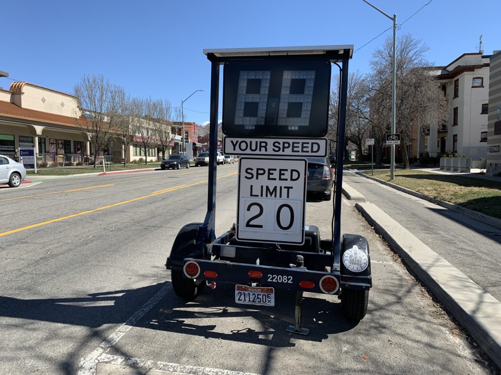 Portable speed monitor with a speed limit sign of 20 on a street.