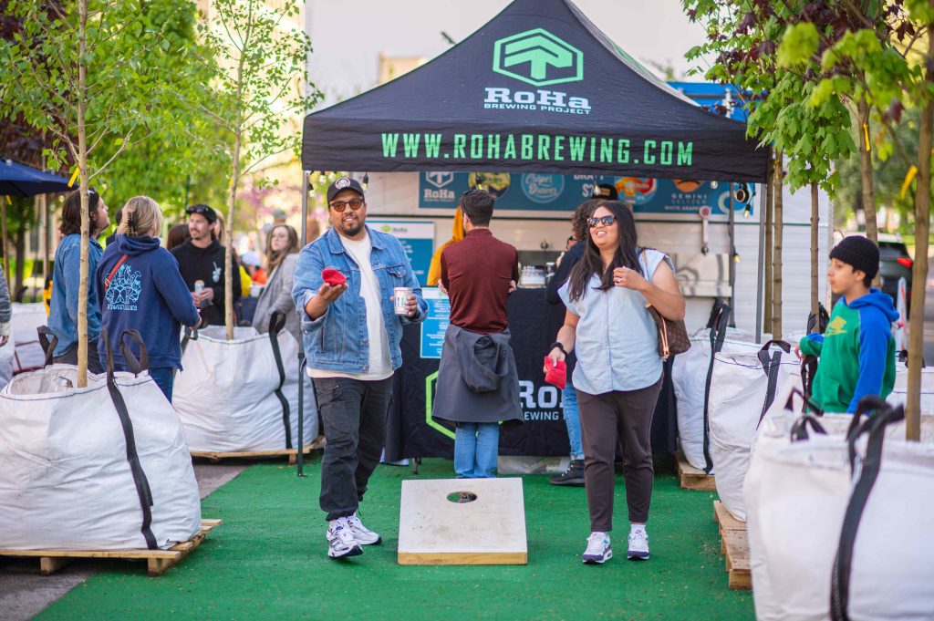 Two people enjoying a drink and playing corn hole at the Green Loop.